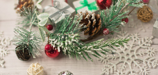 Christmas light gray background on whitewashed wooden boards with green spruce wreath, toys, silver snowflakes and gifts