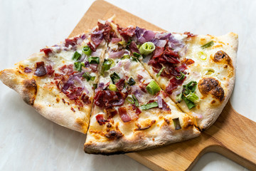 Flammkuchen Pizza Slices / Traditional Tarte Flambee with Creme Fraiche, Cream Cheese, Bacon and Red Onions on Wooden Board.