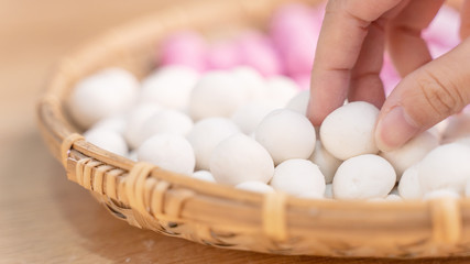 An Asia woman is making Tang yuan, yuan xiao, Chinese traditional food rice dumplings in red and white for lunar new year, winter festival, close up.