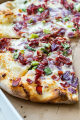 Flammkuchen Pizza Slices / Traditional Tarte Flambee with Creme Fraiche, Cream Cheese, Bacon and Red Onions in Box.