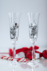 White gift box with red ribbon sweets, champange glasses and decorations on white background. Christmas and New Year holidays concept.