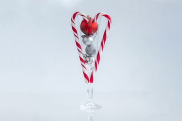 New year and Christmas toys decoration with red bright sweets in shape heart on a champagne glass. Valentines day, love and holidays concept.
