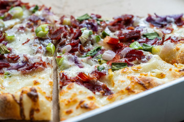 Flammkuchen Pizza Slices / Traditional Tarte Flambee with Creme Fraiche, Cream Cheese, Bacon and Red Onions on Wooden Board.