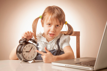Portrait of young attractive business child girl pointing on clock with finger as if she want to say: Don't be late! It's time to work!