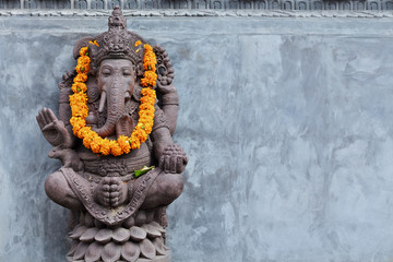 Ganesha sitting in meditating yoga pose in front of hindu temple. Decorated for religious festival...