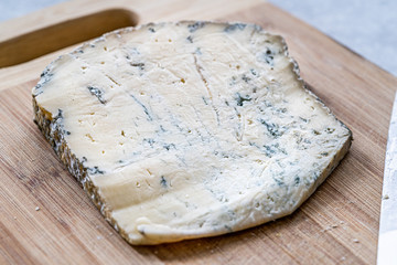 Whole Roquefort French Blue Cheese with Knife on Wooden Board.