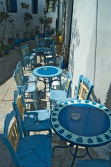 Greece the traditional and beautiful island of Amorgos.  A narrow alley lined with taverna tables and chairs.  The old Chora with it's many pretty, winding streets. 