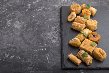 traditional arabic sweets on a black slate board on a black concrete background. side view, copy space.