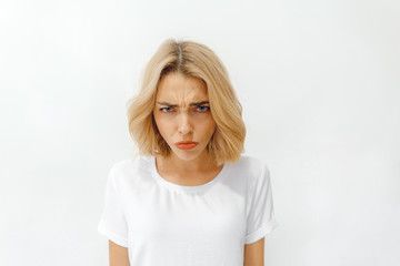 girl shows different emotions. Woman in a white T-shirt on a white background. female shows resentment. copy space