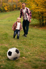 Fototapeta premium Son playing with ball on grass
