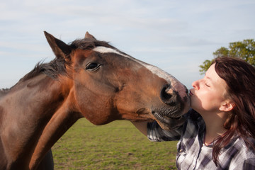 Kisses, young woman and her horse share a loving moment.