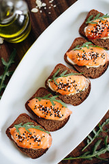 Red fish on rye bread with arugula and sesame. Fish rope. Restaurant appetizer with red fish