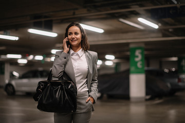 Fototapeta premium Young woman talking on phone on parking 