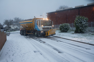 Gritting lorry with snow plough on front clearing roads covered in snow and ice in England UK
