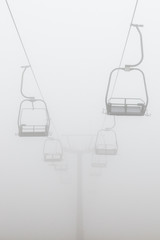 Empty ski chair lift in deep fog in Glen Coe, Scotland. - obrazy, fototapety, plakaty