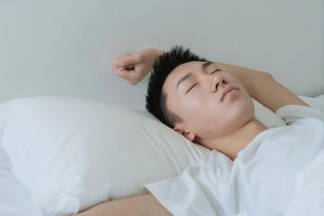 a young man waking up in bed and stretching his arms