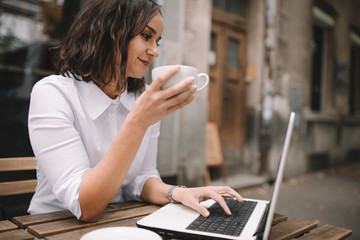 Young businesswoman on coffee break. Beautiful woman working and drinking coffee in cafe. 