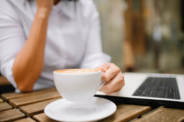 Close up of businesswoman holding cup of coffee and working outdoors. 