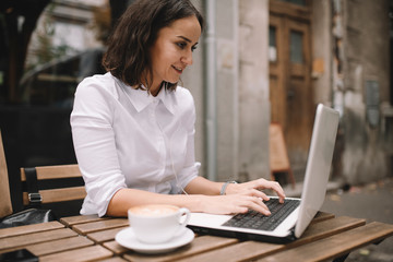Fototapeta premium Young businesswoman working in cafe. Beautiful woman having a video call in coffee shop. 