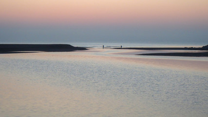Calm and tranquility, two fishermen at the mouth of the river in the sea