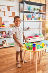 Beautiful african american toddler playing with plastic food and cutlery toy at kindergarten