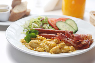 Breakfast scrambled eggs, sausage, fried bacon served with fresh vegetables.