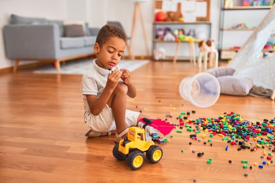Beautiful african american toddler playing with small building blocks at kindergarten