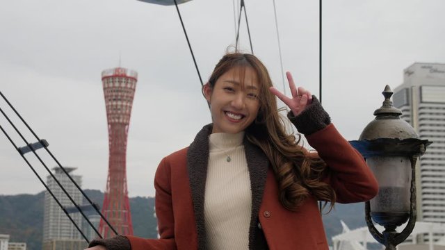 Japanese woman giving peace sigh while on a boat cruse in kobe Japan