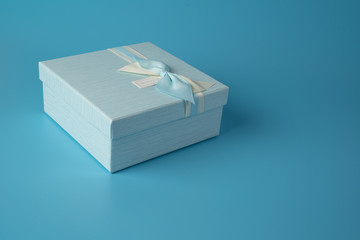 Gift box blue with ribbon and bow on a pale blue background. The concept of a holiday, birthday, the eighth of March.