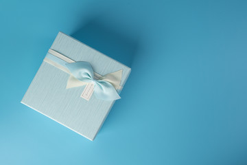 Gift box blue with ribbon and bow on a pale blue background. The concept of a holiday, birthday, the eighth of March.