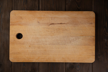 Wooden cutting Board on brown wooden background. The view from the top. Concept to create records, recipes, holiday compositions, birthday, Christmas.