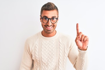 Young handsome man wearing glasses and winter sweater over isolated background surprised with an idea or question pointing finger with happy face, number one
