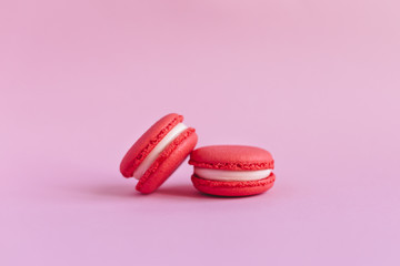 Two tasty french macarons on pink background.