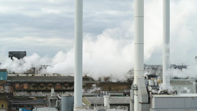 Low aerial view of Paper mill factory with steam and smoke coming from the Victorian infrastructure in the UK.