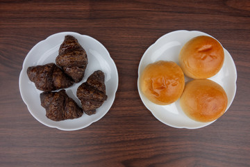 白い皿の上の丸パンとチョコクロワッサン