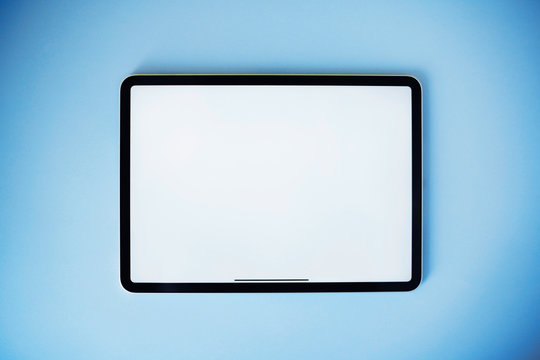 Digital tablet on blue background. Flat lay style. Clean white screen for your text