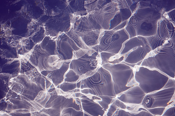 Rippled pattern of clean water in a purple swimming pool for background