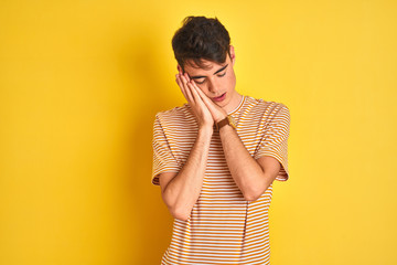 Teenager boy wearing yellow t-shirt over isolated background sleeping tired dreaming and posing with hands together while smiling with closed eyes.