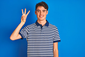 Naklejka premium Teenager boy wearing casual t-shirt standing over blue isolated background showing and pointing up with fingers number three while smiling confident and happy.