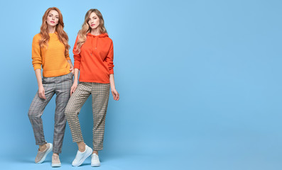 Two easy-going happy hipster Woman smiling, Stylish fashion orange colored outfit. Beautiful Girl...