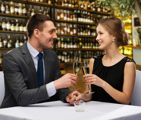 leisure and luxury concept - smiling couple clinking glasses of champagne over restaurant or wine bar background