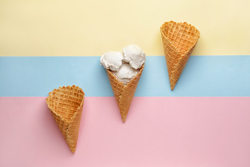 Sweet tasty ice-cream and waffle cones on color background