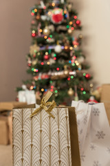 Christmas gist in foreground with Christmas tree blurred in background festive time