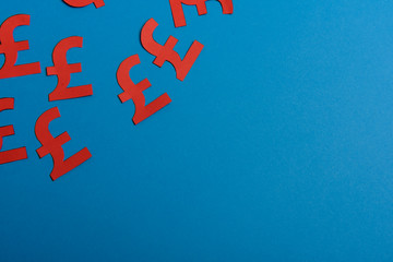 Paper yellow symbols of british pound currency on blue background. View from above with copy space.