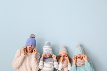 Happy family in winter clothes on color background