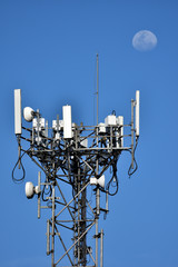 Torre de transmissão de sinal de celular num dia azul e Lua no fundo