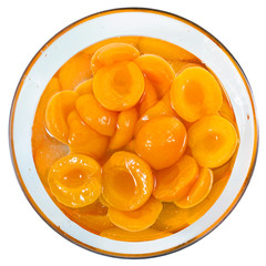 Canned peach halves in syrup in glass bowl isolated on white background. Top view.