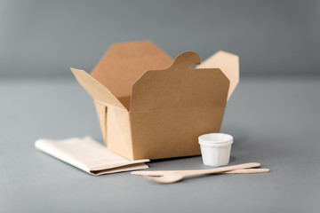 package, recycling and eating concept - disposable box for takeaway food with wooden fork, knife...