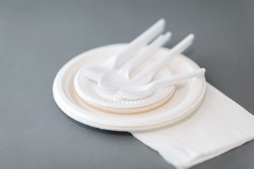 eating, recycling and ecology concept - disposable paper plates and plastic spoons, knives and...