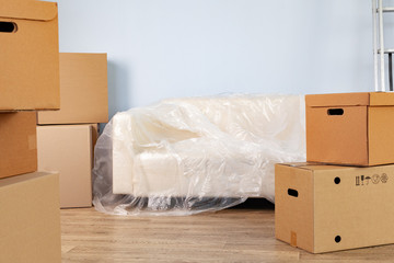 Packed household stuff in boxes and packed sofa for moving